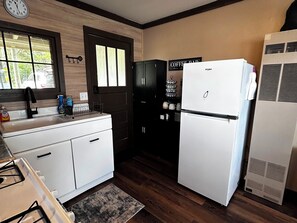A kitchen with a white refrigerator, a sink with a faucet, and a window with blinds. - Charming Renovated Northwoods Cabin on Chetek Chain of Lakes (Chetek)