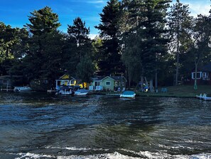 A lakeside property with multiple boats docked, surrounded by trees and houses. - Charming Renovated Northwoods Cabin on Chetek Chain of Lakes (Chetek)