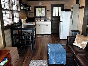 A compact kitchen with a dining area, a refrigerator, and a coffee machine. - Charming Renovated Northwoods Cabin on Chetek Chain of Lakes (Chetek)