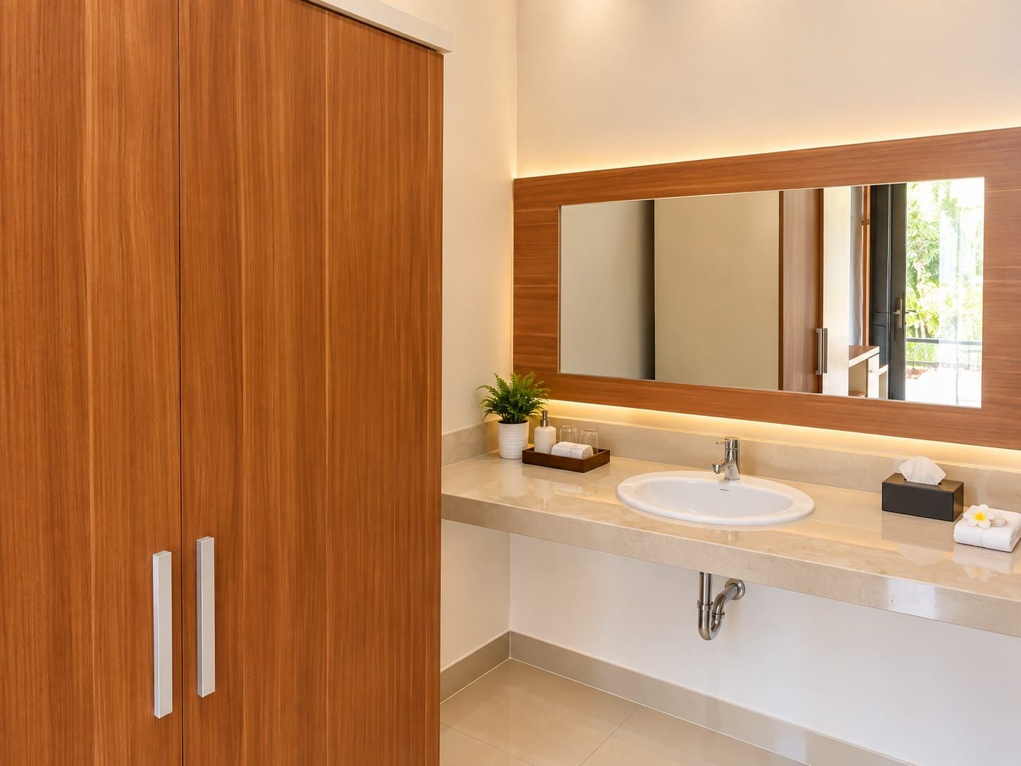 A modern bathroom with a wooden vanity, a large mirror, and a sink.