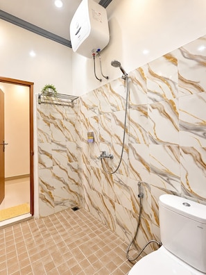 A bathroom with a shower, toilet, and a water heater. - Telaga Garden Hotel (Sumbawa Barat)