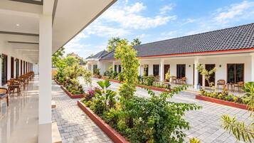 A hotel courtyard with tiled flooring, outdoor seating, and lush greenery.