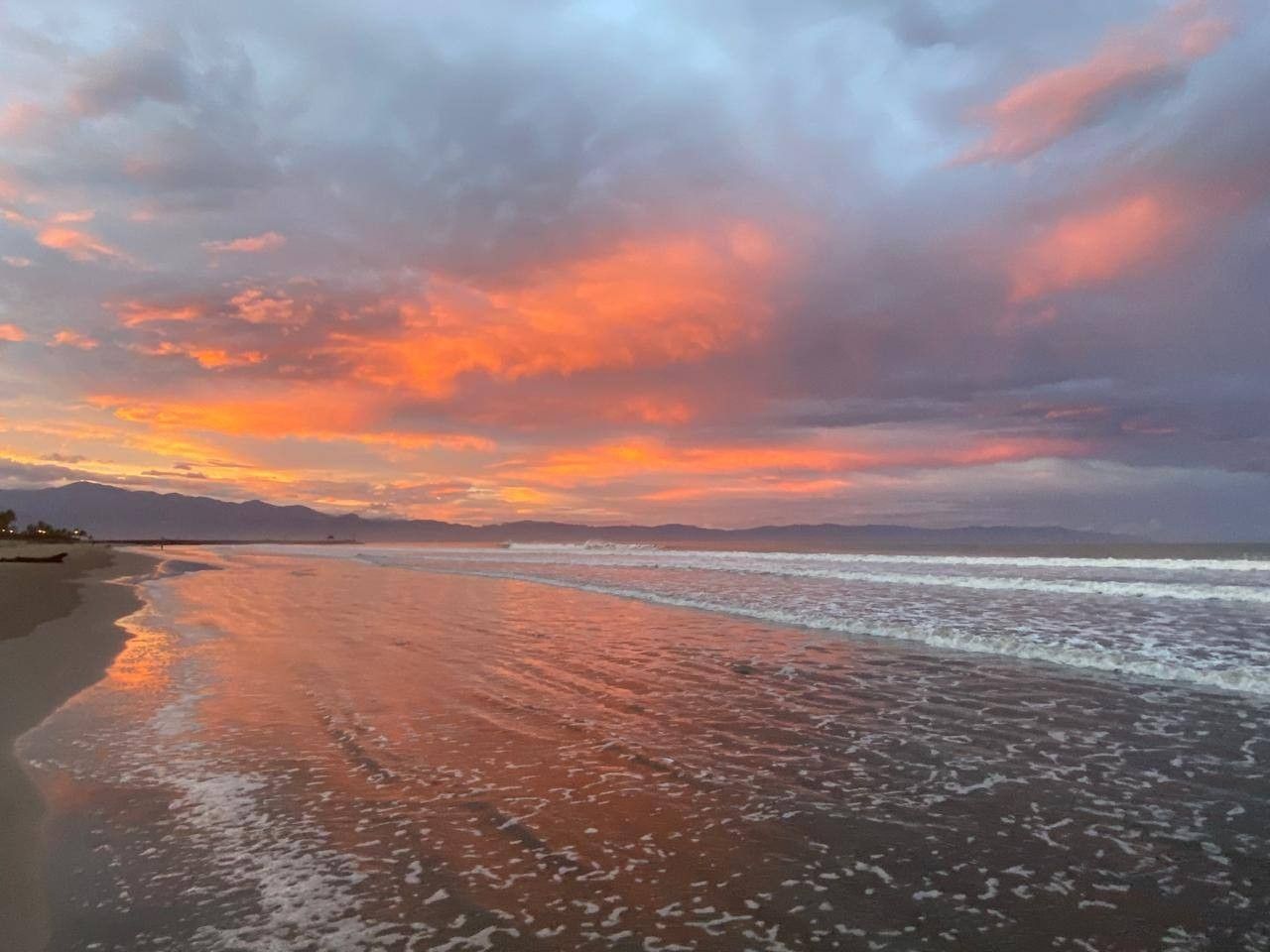 A beach with a calm sea and a sunset sky.