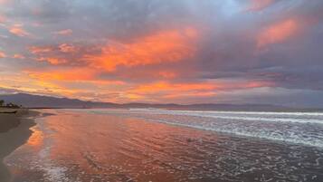 A beach with a calm sea and a sunset sky.