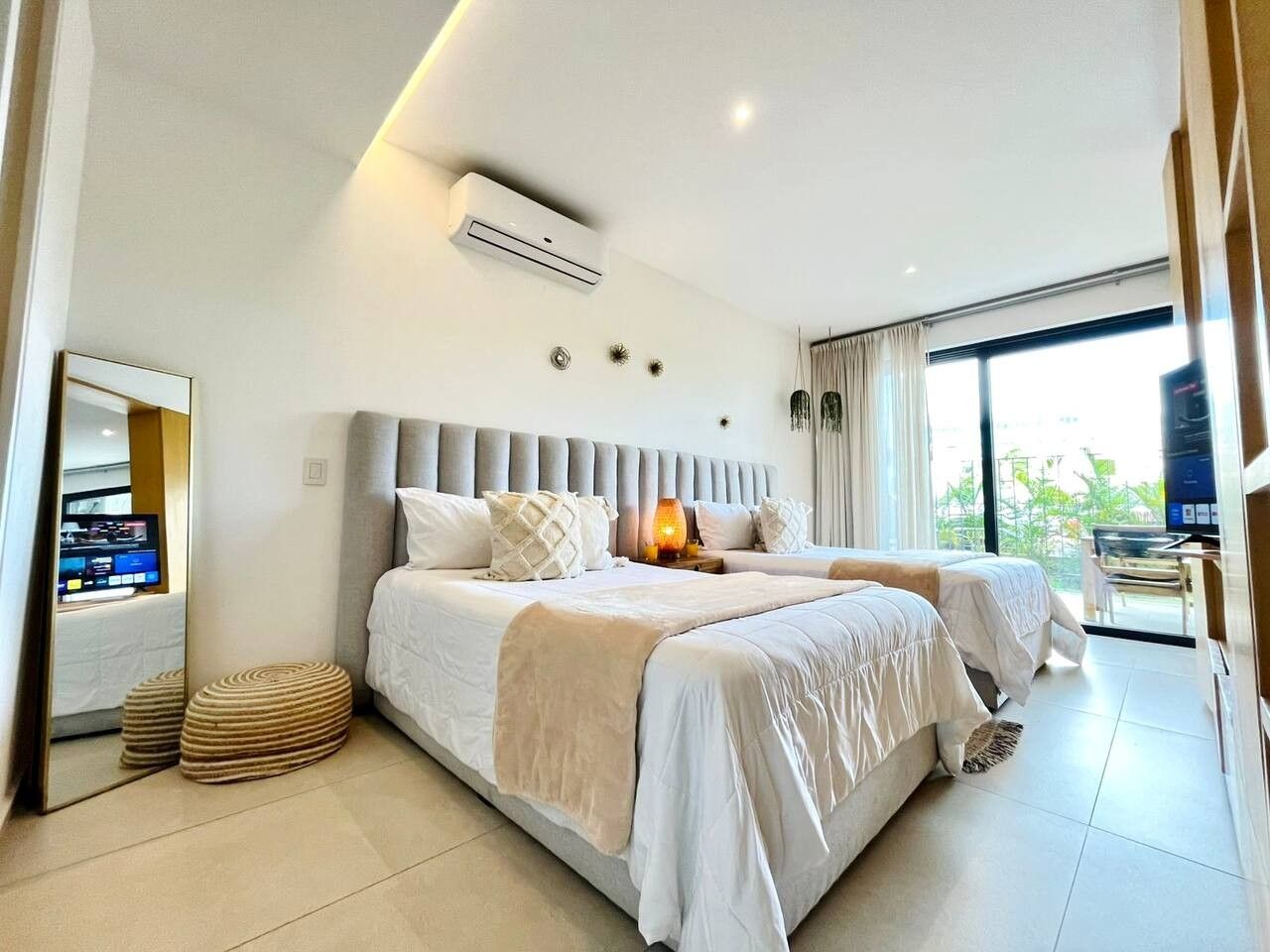 A hotel room with a large bed, a television, and a view of the outdoors.