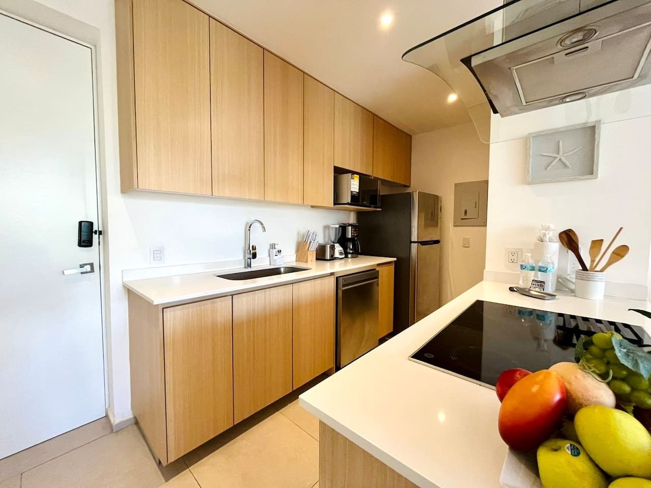 A modern kitchen with wooden cabinets, a built-in dishwasher, and a black induction cooktop.