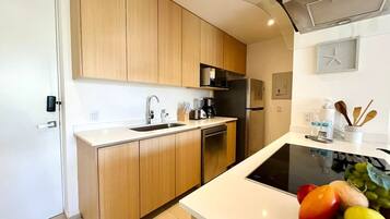 A modern kitchen with wooden cabinets, a built-in dishwasher, and a black induction cooktop.
