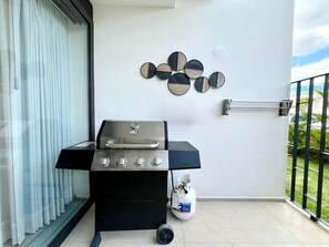 Un balcone con una griglia barbecue, una bombola di gas e un elemento decorativo a parete.