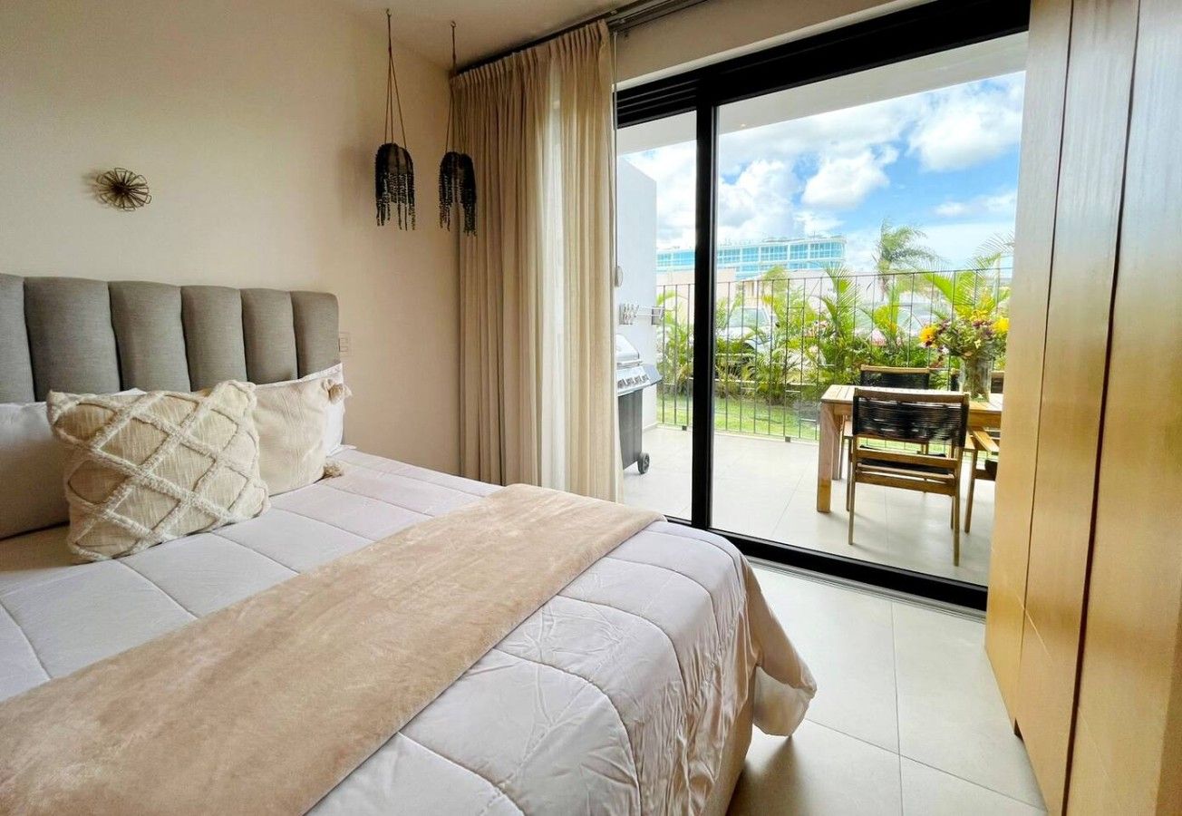 Une chambre d’hôtel avec un grand lit, un balcon offrant une vue sur la ville et un coin repas.