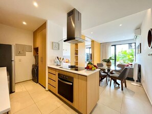 Una cucina moderna con isola centrale, forno a incasso e cappa aspirante in acciaio inox.