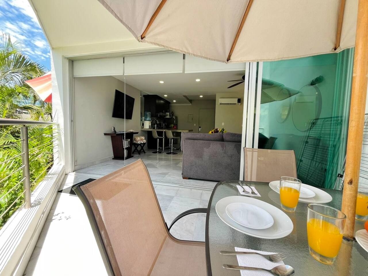An outdoor dining area with a table set for two, a sofa, and a view of the kitchen and living area.