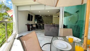An outdoor dining area with a table set for two, a sofa, and a view of the kitchen and living area.