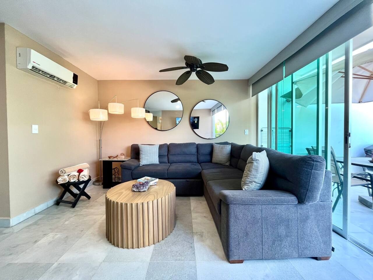 A modern living room with a sectional sofa, a round coffee table, and a ceiling fan.