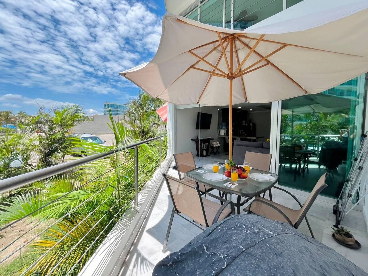 A balcony with a table, chairs, and a large umbrella.