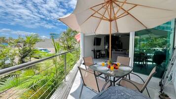 A balcony with a table, chairs, and a large umbrella.