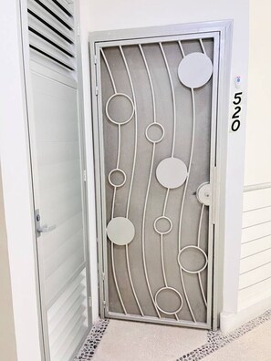 Una puerta con una celosía metálica decorativa que presenta diseños circulares y curvos.