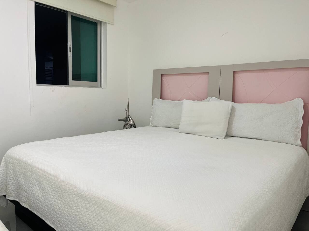 Una habitación de hotel estándar con una cama individual, ventana y mesita de noche.