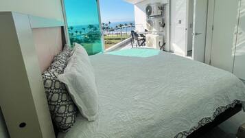 Une chambre avec un lit, une vue sur l’océan et un balcon équipé d’une table et de chaises.