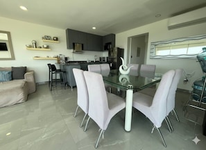 A modern kitchen with grey cabinets, a central island, and a dining area with a glass table and four chairs. - 520 sea view apartment in Nuevo Vallarta (Nuevo Vallarta)