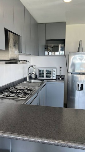 A modern kitchen with a gas stove, a microwave, and a stainless steel refrigerator. - 520 sea view apartment in Nuevo Vallarta (Nuevo Vallarta)