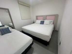 A hotel room with two beds, a mirror, a bedside table, and a window with a blind. - 520 sea view apartment in Nuevo Vallarta (Nuevo Vallarta)