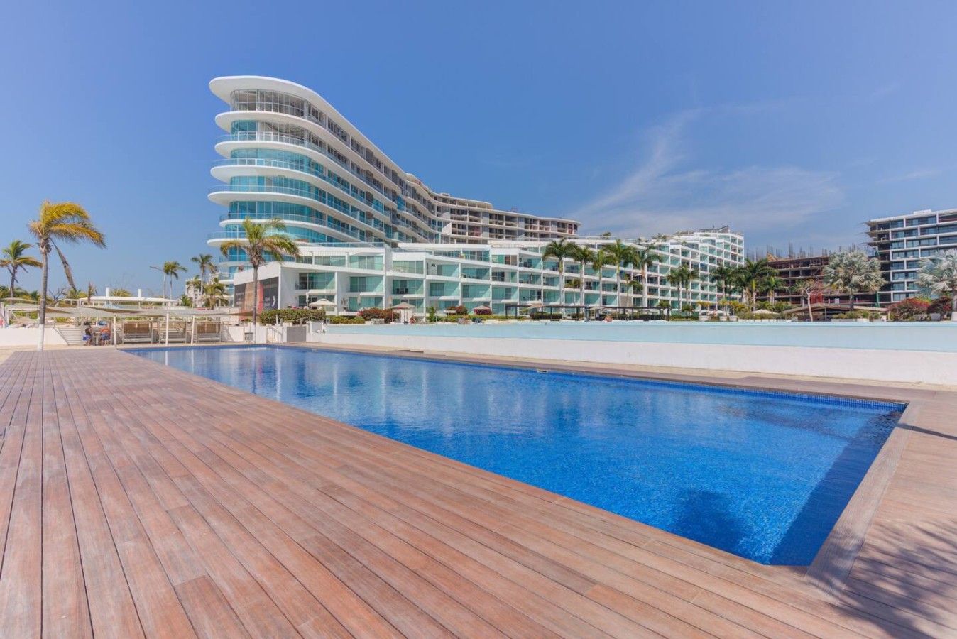 Um hotel moderno com área de piscina, apresentando um deck de madeira e uma piscina azul cristalina.