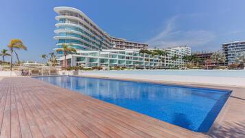 Um hotel moderno com área de piscina, apresentando um deck de madeira e uma piscina azul cristalina.