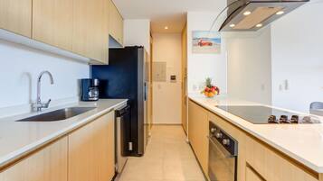A modern kitchen with wooden cabinets, stainless steel appliances, and a fruit bowl on the counter.