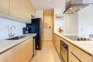 Une cuisine moderne avec des meubles en bois, des appareils en acier inoxydable et un panier de fruits posé sur le plan de travail.