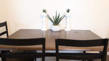 Een eettafel met twee stoelen, een centrale potplant en twee witte kandelaars.