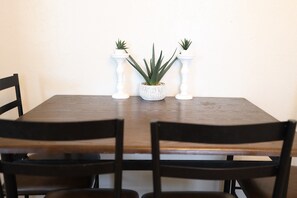 Una mesa de comedor con dos sillas, una planta en maceta en el centro y dos candelabros blancos.