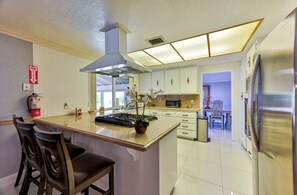 A modern kitchen with a central island, stainless steel appliances, and a fire extinguisher on the wall. - La Rosa Estate: Hacienda Getaway w/ Indoor Pool, Jacuzzi & Vintage Billiards (Las Vegas)