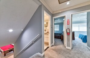 A hallway with a pool table, a fire extinguisher, and a bedroom with a bed and a blue blanket. - La Rosa Estate: Hacienda Getaway w/ Indoor Pool, Jacuzzi & Vintage Billiards (Las Vegas)