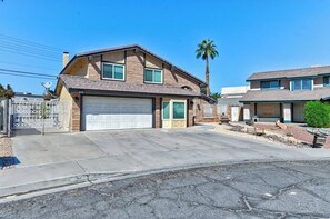 A two-story house with a garage, a driveway, and a palm tree. - La Rosa Estate: Hacienda Getaway w/ Indoor Pool, Jacuzzi & Vintage Billiards (Las Vegas)