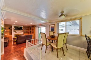 A spacious living area with a fireplace, a television, and a dining table with chairs. - La Rosa Estate: Hacienda Getaway w/ Indoor Pool, Jacuzzi & Vintage Billiards (Las Vegas)