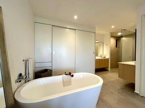Un baño moderno con una bañera independiente, un espejo grande y una ducha a ras de suelo.