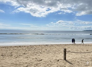 Una playa arenosa con un poste de madera y una barrera de cuerda.