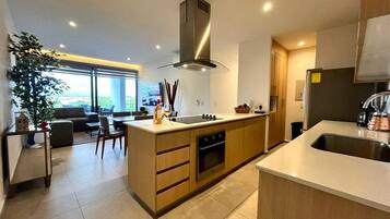 Een moderne keuken met een centraal kookeiland, een inbouwoven en roestvrijstalen apparatuur.