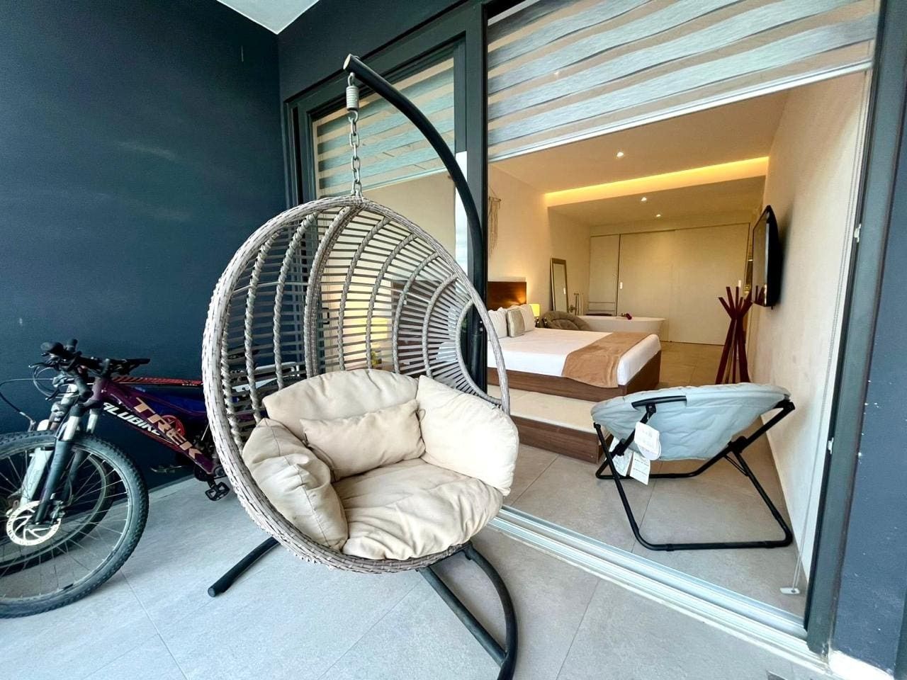 Een modern interieur met een hangstoel, een fiets en een opgemaakt bed.