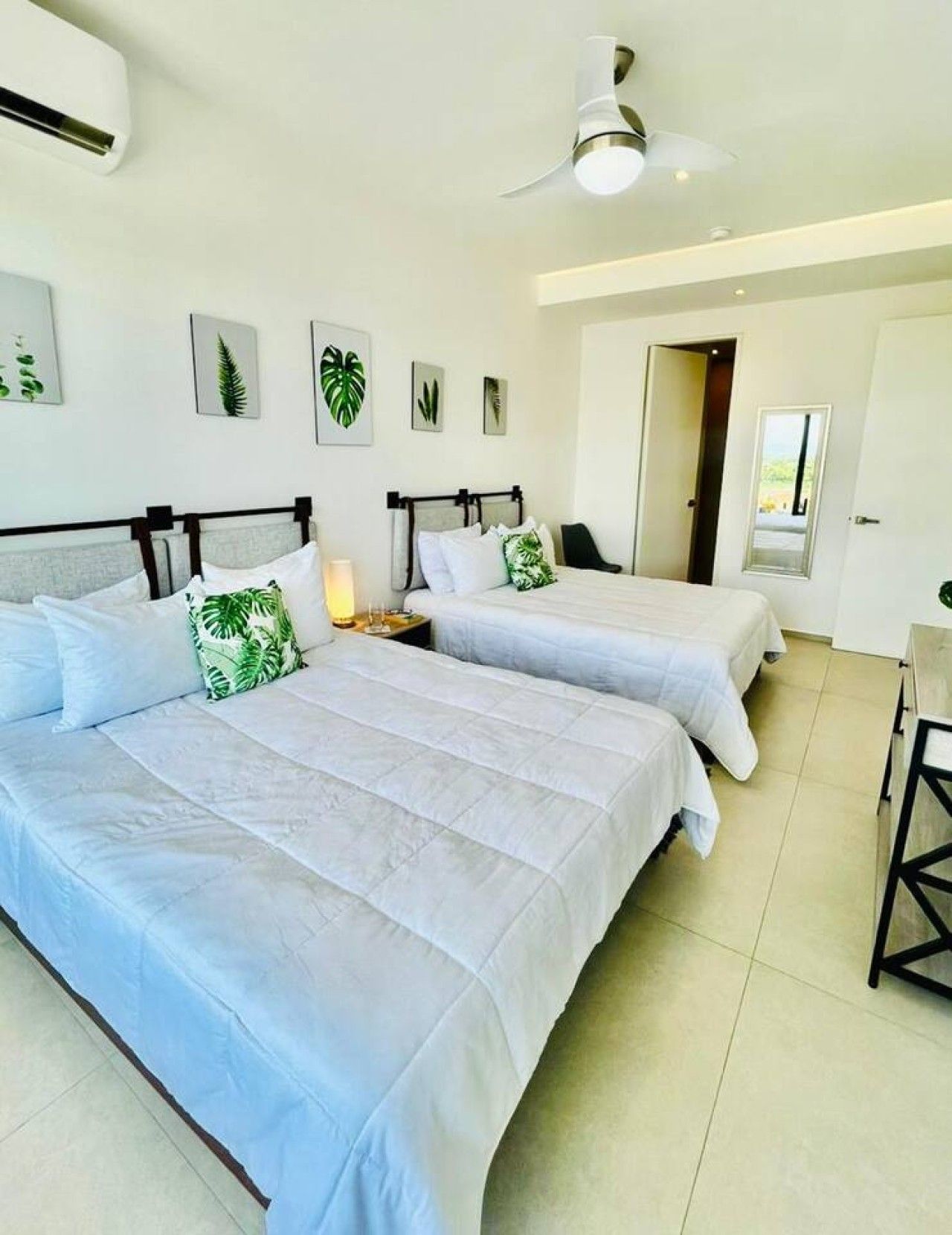 Une chambre d’hôtel avec deux lits, un ventilateur de plafond et des œuvres d’art murales.