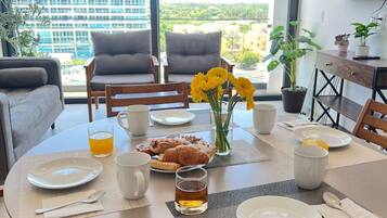 Un coin repas avec une table ronde mise pour le petit-déjeuner, comprenant des assiettes, des tasses et un verre de jus de fruits.
