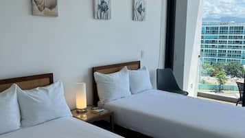 Habitación de hotel con dos camas, una mesita de noche con lámpara y una obra de arte en la pared.