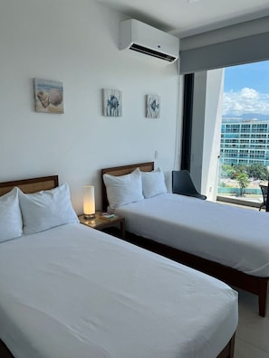 Habitación de hotel con dos camas, una mesita de noche con lámpara y una obra de arte en la pared.