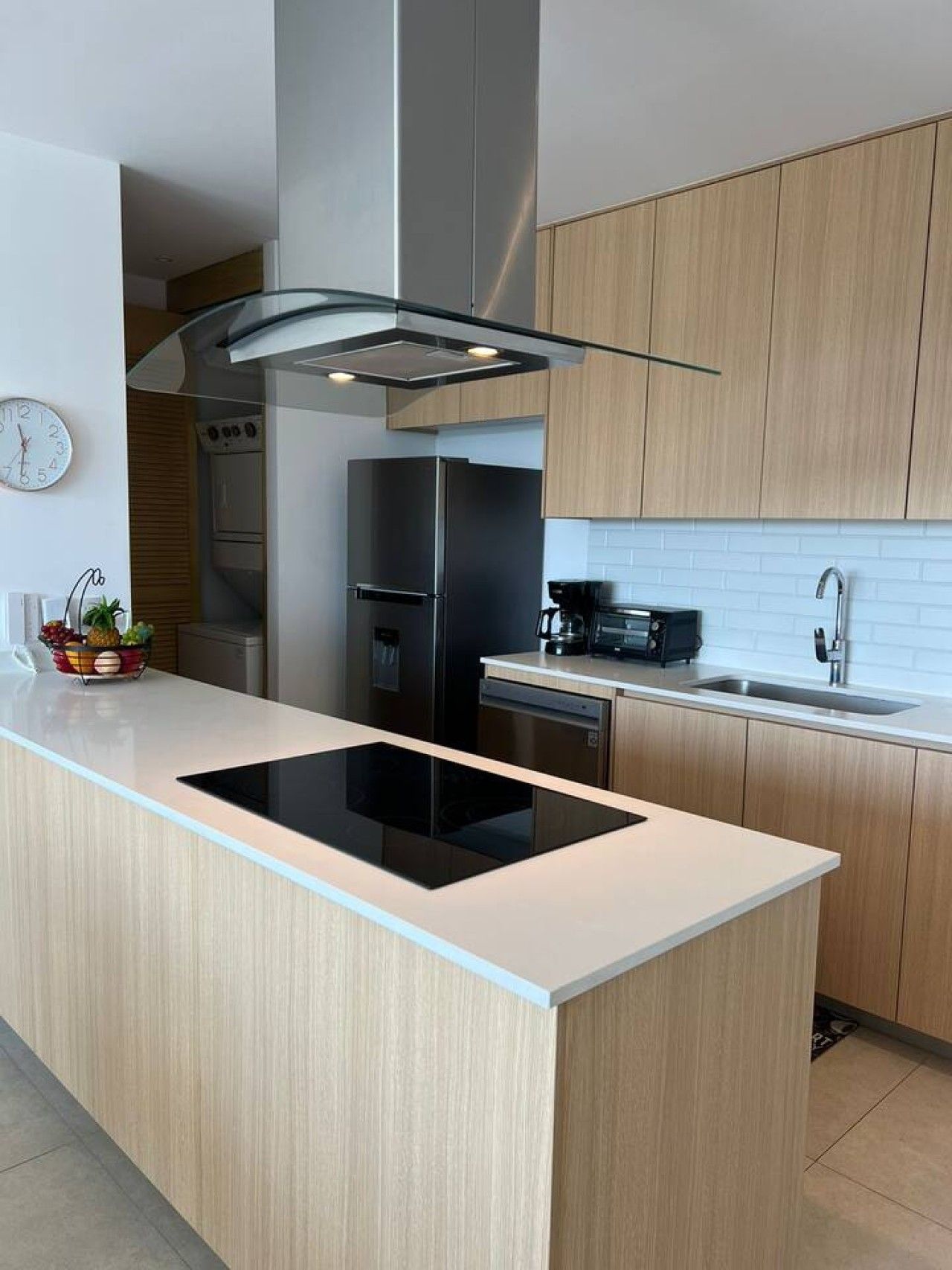 A modern kitchen with a central island, built-in appliances, and wooden cabinetry.