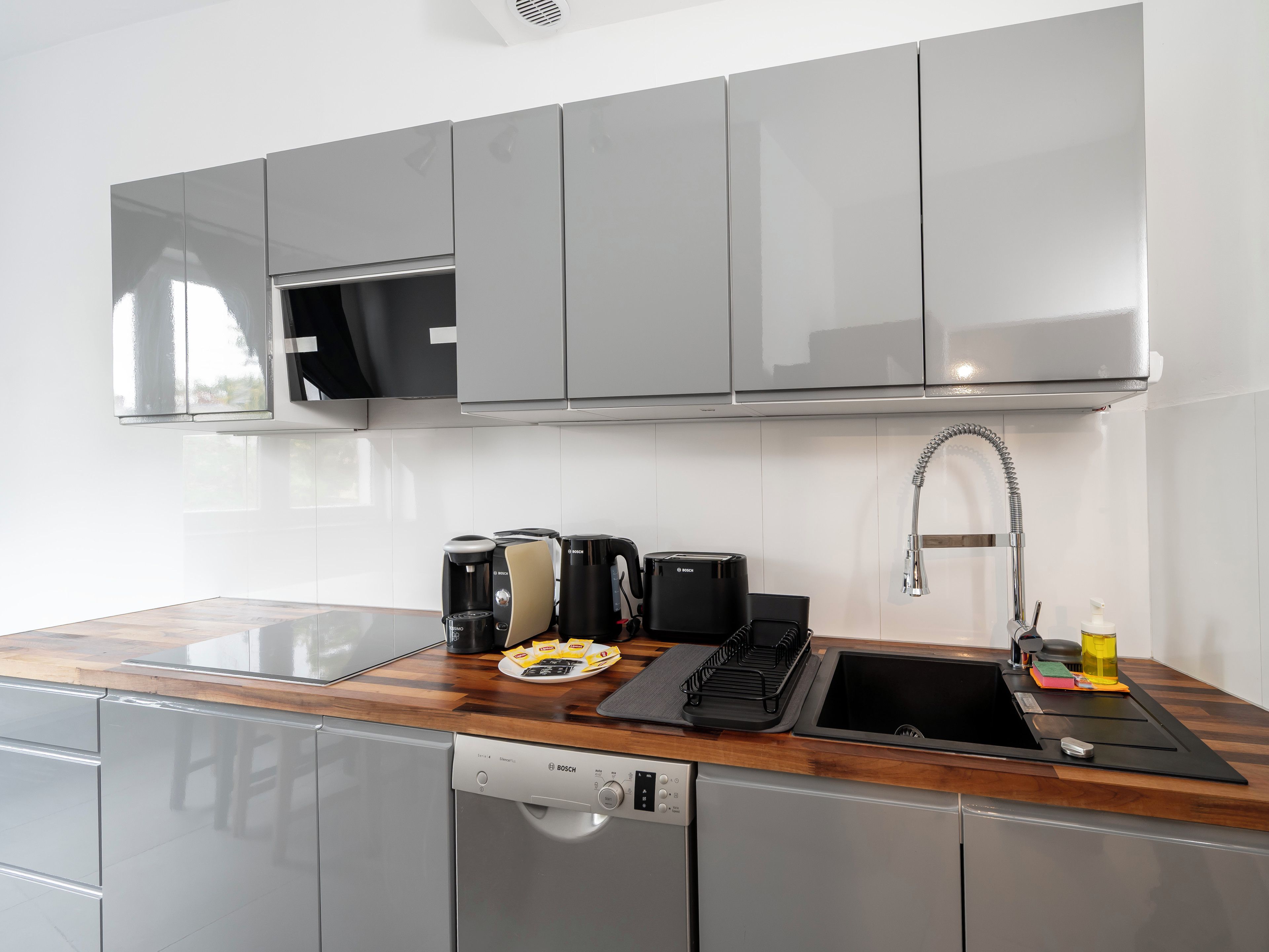 Una cocina moderna con electrodomésticos de acero inoxidable, lavavajillas y microondas empotrado.