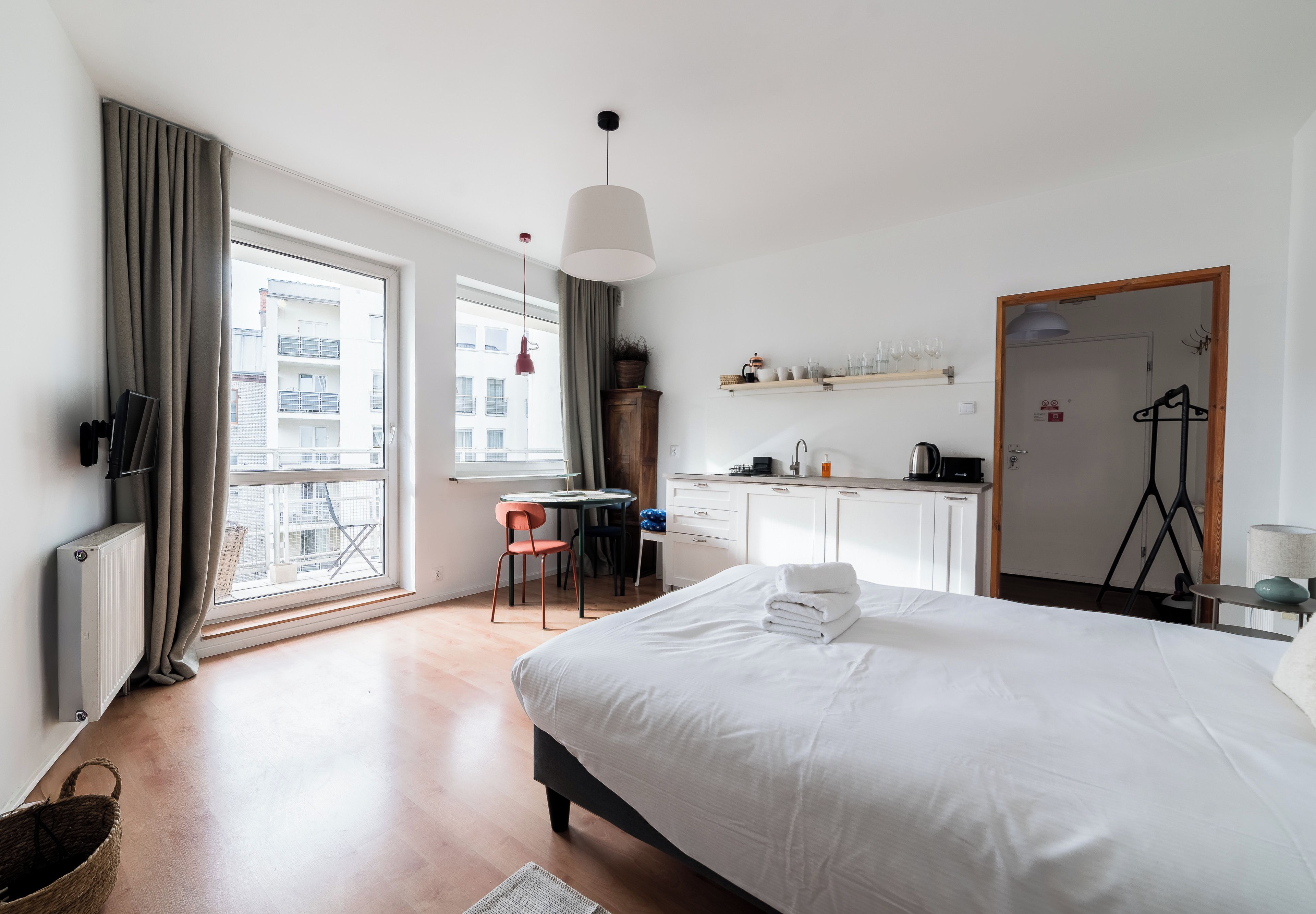 Une chambre d’hôtel avec un lit, un bureau, une chaise, une fenêtre avec des rideaux, un radiateur et une porte.
