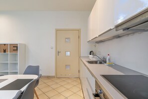 A compact kitchen with a stove, sink, and storage cabinets. - Zwycięstwa Comfort Apartment (Gliwice)