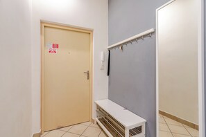 A hallway with a beige door, a white bench, and a wall-mounted telephone. - Zwycięstwa Comfort Apartment (Gliwice)