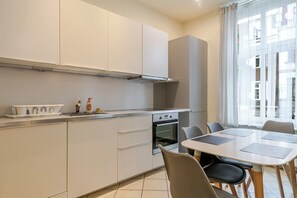 Una cocina moderna con horno empotrado, un comedor con mesa y sillas, y vistas al exterior a través de amplios ventanales.