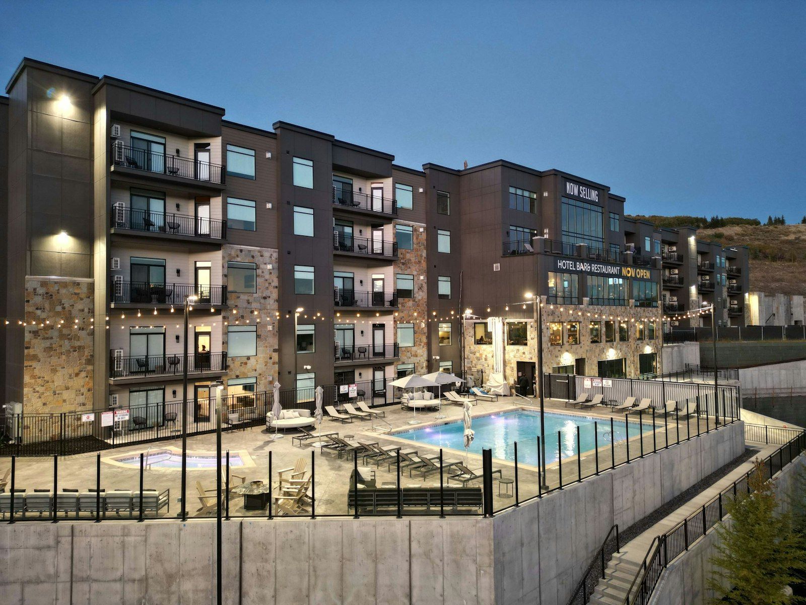 A multi-story hotel with balconies, a swimming pool, and outdoor seating.